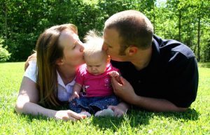 Young family together, kissing baby